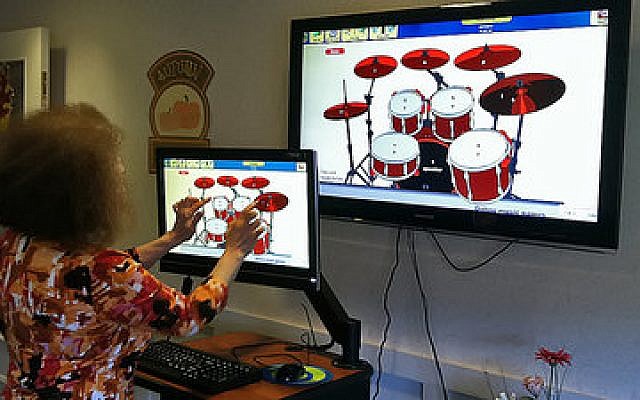 A resident of the LHAS Arbor Unit at Weinberg Village makes music with a virtual set of drums using the unit’s new iN2L computer system. The system has proven to be a valuable therapeutic tool while enriching the lives of residents in the Arbor Unit. (JAA photo)