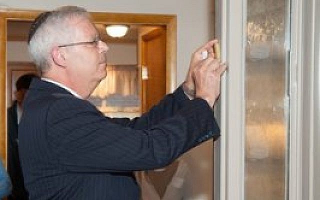Rabbi Eli Seidman affixing the mezuzah to the front door of the Solomon and Sarah Goldberg House at the ceremony on Sept. 16. (Photo provided)