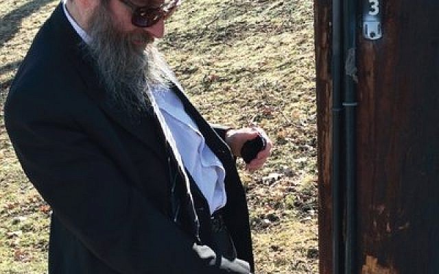 Rabbi Shimon Silver checks an electric pole on which part of the eruv is attached. Silver, spiritual leader of Young Israel of Pittsburgh, is supervisor of the community eruv.  (Photo by Toby Tabachnick)
