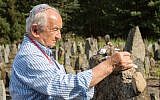 Holocaust survivor Howard Chandler places a stone on a grave in Poland.
(Photo provided by Zipora Gur)