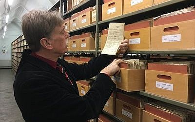 Hans-Hermann Söchtig, director of the German government agency Deutsche Dienststelle, examines a folder in the WASt archives, which help descendants 
of Nazi soldiers learn more about their father’s or grandfather’s wartime service. 

Photo by Orit Arfa