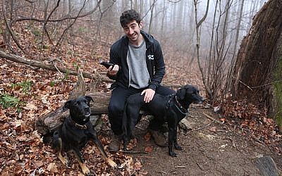 Kenny Gould holds a beer while seated beside his two dogs.	Photo courtesy of Hop Culture