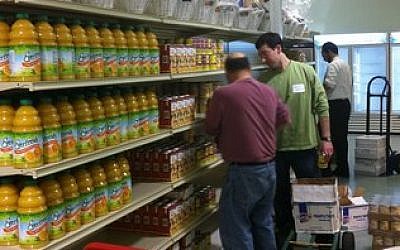 Shalom Pittsburgh volunteers Jon Halpern (left) and Greg Unatin stock shelves Sunday at the Squirrel Hill Community Food Pantry. (JF&CS photo)