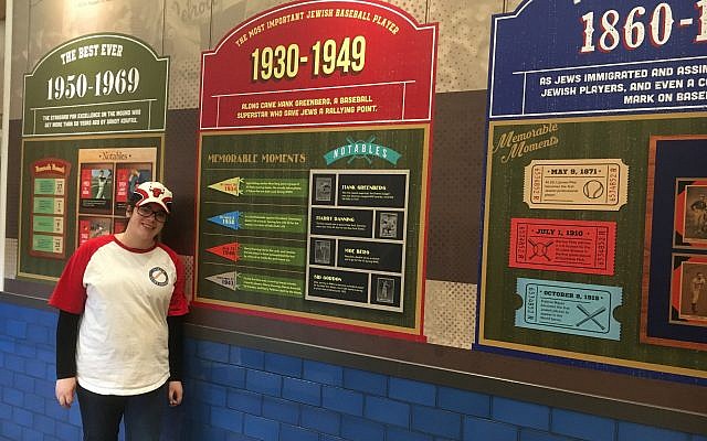 Deli worker Zahava Auerbach poses next to an exhibit at the Jewish baseball museum at Milt’s Extra Innings in Chicago. (Photo by Ellen Braunstein)