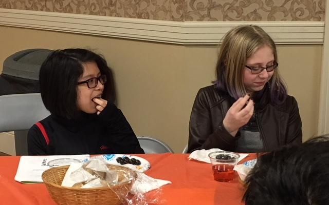 Hannah Dunn and Rebecca Gerse learn the correct blessing for eating olives at the Weiger School as part of its Tu B’Shevat 
celebration. (Photo courtesy of Temple David)