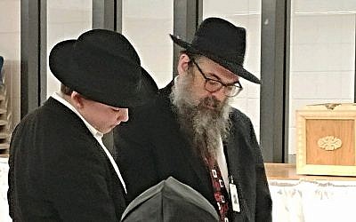 Yankel Vogel, left, reads the Megillah to Jewish prisoners as his father, Rabbi Moishe Mayer Vogel, looks on. With new restrictions, the rabbi fears access to Jewish prisoners may be more difficult in some state prisons across the nation. (Photo by Kimberly Greway)