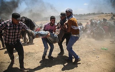 Palestinians carrying a wounded man during a protest against United States’ plans to relocate its embassy from Tel Aviv to Jerusalem, near Al Bureij Refugee Camp at the Gaza-Israel border, May 14, 2018. (Photo by Hassan Jedi/Anadolu Agency/Getty Images)