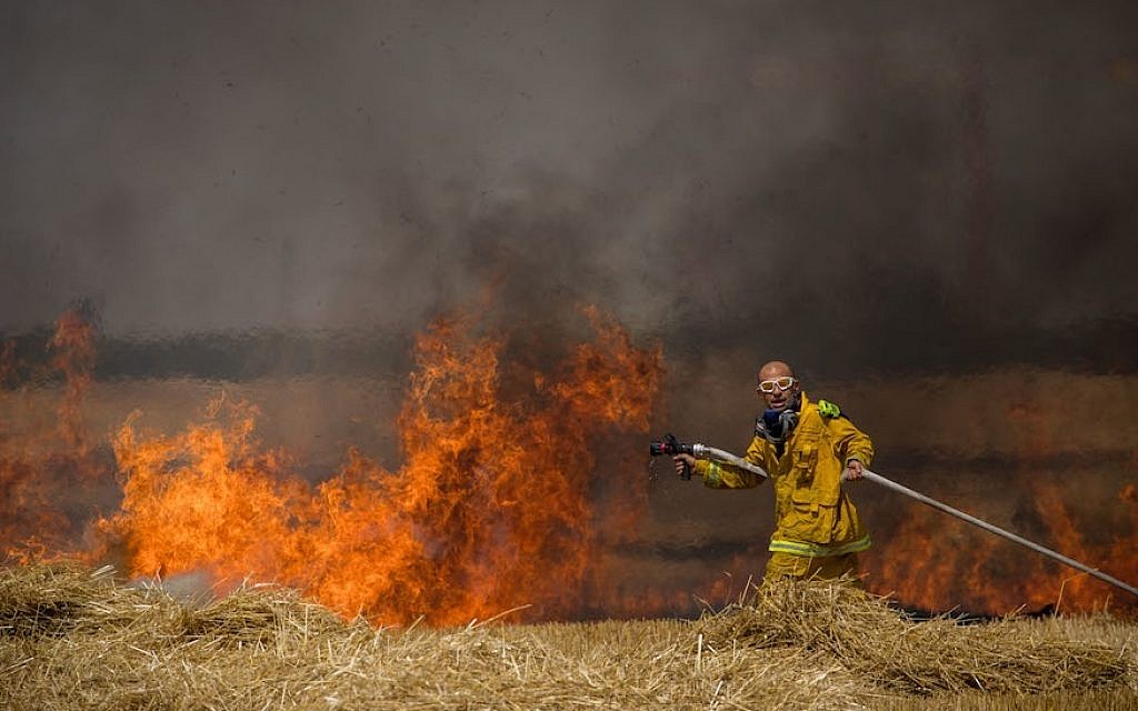 Israeli firefighters extinguish a fire in a wheat field caused from kites flown by Palestinian protesters, near the border with the Gaza Strip, May 30, 2018. (Photo by Yonatan Sindel/Flash90)