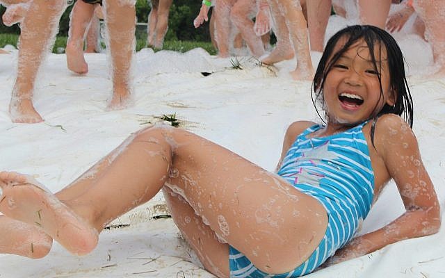 Joanna Huang, Sabra camper, enjoys the slip ‘n’ slide during the Foam Party. The Foam Party is a new activity offered to campers in grades 2-6 at the Emma Kaufmann Camp. (Photo courtesy of the Jewish Community Center of Greater Pittsburgh)