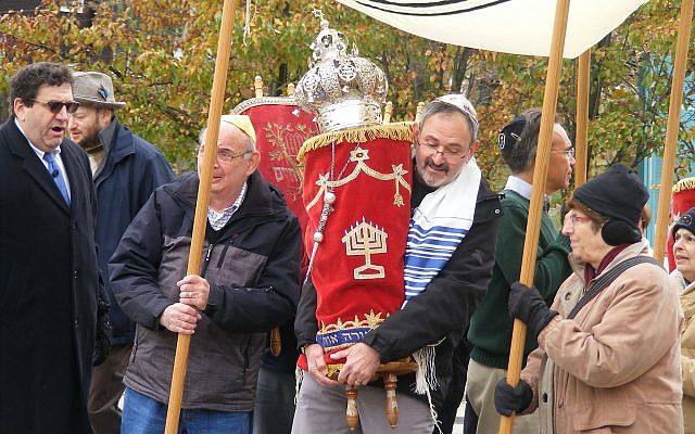 Dr. Richard Gottfried carries the Torah during a procession from New Light Congregation's old building toward their new space.  (Photo by Barry Werber)
