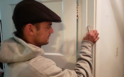 Carnegie Mellon University student Sam Adidas hangs a mezuzah, delivered by Chabad at CMU, onto his doorpost.		(Photo provided by Rabbi Yisroel Altein)