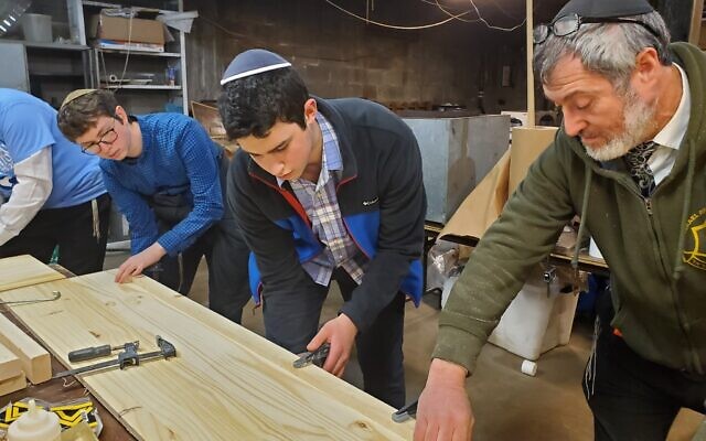 Rabbi Daniel Wasserman teaches students how to clamp boards for a casket. (Photo by Adam Reinherz)