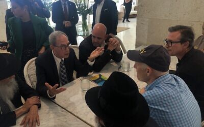 Nachman Shai, second from left, speaks to Sen. Rick Scott, in cap, at the Grand Beach Hotel in Surfside, Fla., June 27, 2021. (Ron Kampeas)
