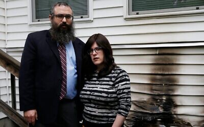 Rabbi Mendy Krinsky and his wife, Chanie, of the Chabad Jewish Center in Needham, Massachusetts, pose beside the spot where someone tried to set their Chabad house on fire in May 2019. (Jessica Rinaldi/The Boston Globe via Getty Images)