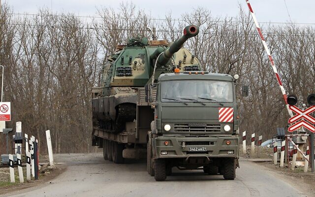 An army truck carries a self-propelled howitzer in Pokrovskoye, Russia, Feb. 21, 2022. (Stringer\TASS via Getty Images)