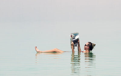 A tourist poses for a picture while floating in the Dead Sea in Israel on June 17, 2018. (Photo by Ronen Tivony/NurPhoto via Getty Images)