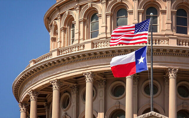 U.S. and Texas state flags flying on the dome of the Texas State Capitol building in Austin. (Photo by CrackerClips Stock Media/Shutterstock)