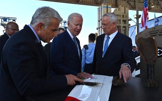 Defense Minister Benny Gantz, right, presents US President Joe Biden with the wing of a drone intercepted by the Iron Beam laser defense system, as Prime Minister Yair Lapid (L) looks on at the Ben Gurion Airport, July 13, 2022. (Ariel Hermoni/Defense Ministry)