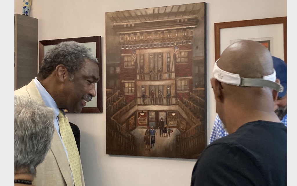Manchester Bidwell Corp. President and CEO Bill Strickland at the entrance of the newly reopened Kaufmann Center, beside Shelly Blumenfeld’s painting “Irene Kaufmann Settlement House” and a salvaged section of the old settlement house pool. (Photo courtesy of Eric Lidji)