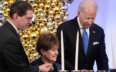 Rabbi Charlie Cytron-Walker and US President Joe Biden help Holocaust Survivor Bronia Brandman to a menorah during a Hanukkah Holiday Reception in t