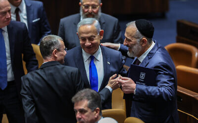 Benjamin Netanyahu, center, with Aryeh Deri, right, and other lawmakers at a plenum session on forming the government, in the Israeli parliament in Jerusalem, Dec. 29, 2022. (Yonatan Sindel/Flash90)