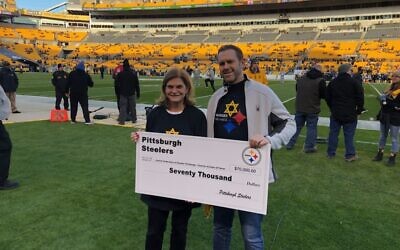 Former Jewish Federation of Greater Pittsburgh chair Meryl Ainsman, seen with Tim Hindes who designed the Stronger than Hate t-shirt, accept a $70,000 donation to the Jewish Federation of Greater Pittsburgh's Victims of Terror fund from the Pittsburgh Steelers. Photo provided by Tim Hindes