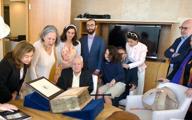 Alfred Moses (center, seated) examines the Codex Sassoon surrounded by family and friends. (Perry Bindelglass for The American Friends of ANU The Museum of the Jewish People)