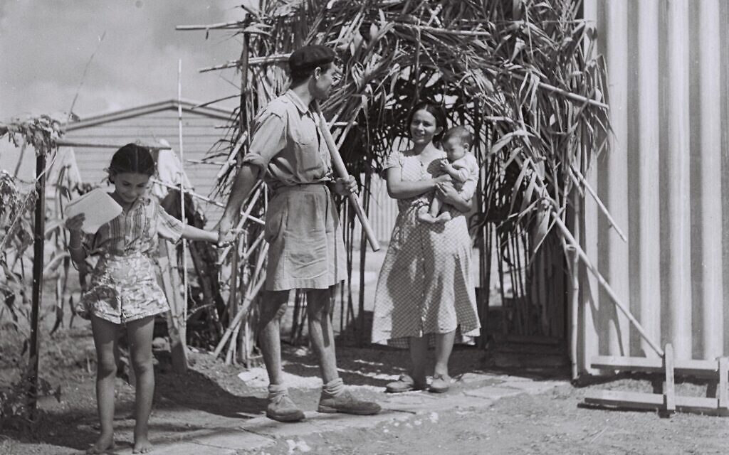 A young family standing outside the modest sukkah they built for the holiday, Israel, 1949 (Photo courtesy of the Government Press Office, Israel, via Wikimedia Commons)