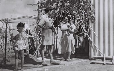 A young family standing outside the modest sukkah they built for the holiday, Israel, 1949 (Photo courtesy of the Government Press Office, Israel, via Wikimedia Commons)