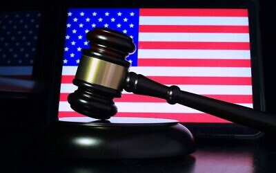 A gavel in front of a screen displaying the U.S. flag. (Credit: Sergei Tokmakov/Pixabay)