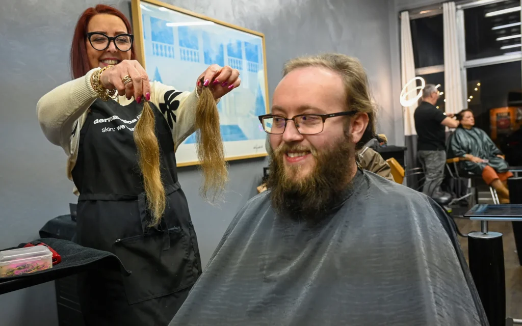 Patty Knapp, hair stylist at Cadamone's Salon in Regent Square, shows Andrew Goldstein locks of hair she'd just cut from his head on Tuesday, Nov. 18, 2025. This was Goldstein's first haircut since he and his fellow members of the Newspaper Guild of Pittsburgh went on strike at the Post-Gazette in October 2022. (Steve Mellon/Pittsburgh Union Progress)