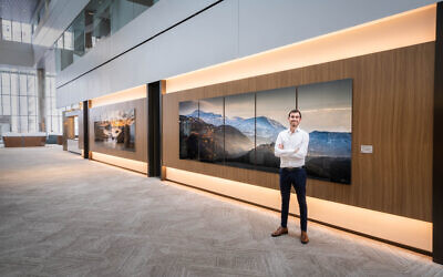 Artist Yehoshua Aryeh Stauber stands before one of his Israel landscape photos at One Oxford Centre (Photo by Ya Momz House, Inc.)