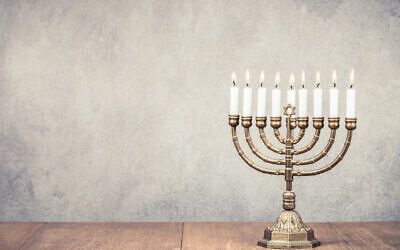 Bronze Hanukkah menorah with burning candles on wooden table. (BrAt_PiKaChU, courtesy of flickr.com)