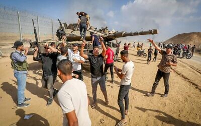 Palestinians take control of an IDF tank after breaching the Israeli border fence from Khan Yunis in the southern Gaza Strip, Oct. 7, 2023. (Photo by Abed Rahim Khatib/Flash90)