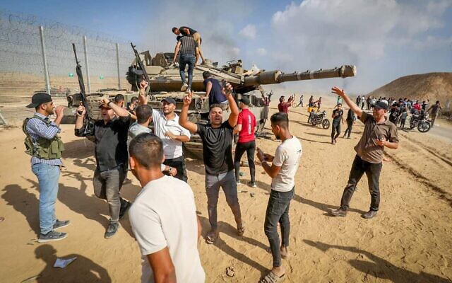 Palestinians take control of an IDF tank after breaching the Israeli border fence from Khan Yunis in the southern Gaza Strip, Oct. 7, 2023. (Photo by Abed Rahim Khatib/Flash90)