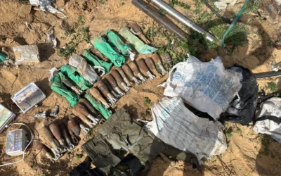 Mortar shells and other munitions sit alongside the UNRWA-marked aid bags they were found in by Israeli forces in the southern Gaza Strip. (Credit: IDF)