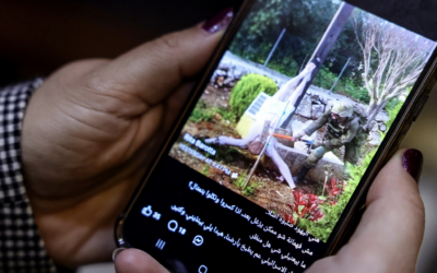 A woman checks a social media post on her mobile phone featuring an image that appears to show an Israeli soldier hitting a statue of Jesus Christ in the southern Lebanese Christian village of Debl, in Beirut on April 20, 2026. (Anwar AMRO / AFP)