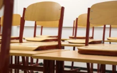 Chairs propped up on desks in an empty classroom. (Credit: Taken/Pixabay)