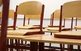 Chairs propped up on desks in an empty classroom (Credit: Taken/Pixabay)