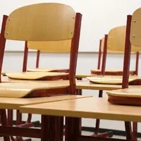Chairs propped up on desks in an empty classroom (Credit: Taken/Pixabay)