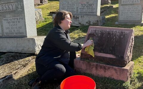 In preparation of Oct. 27, a volunteer helps clean a cemetery. (Photo courtesy of Jewish Cemetery & Burial Association)