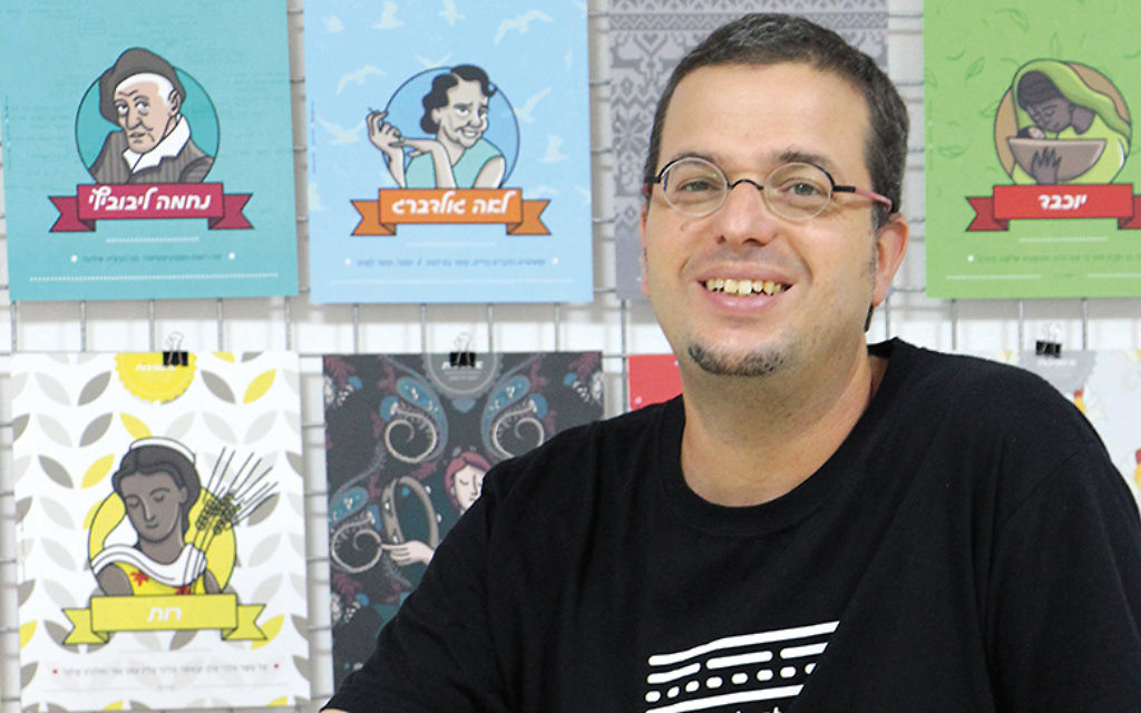 Dov Abramson poses in his Jerusalem studio in front of the ushpizot posters his team created. (Maoz Vaystooch.)