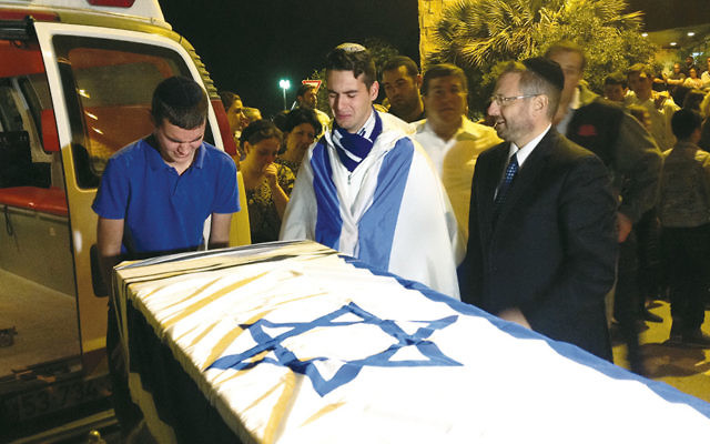 Some of Ezra Schwartz’s many friends mourn over the coffin of the American terror victim at a service at Ben Gurion Airport in Israel before the body was repatriated to Boston for his funeral the following day, November 21. (JTA/Ben Sales)