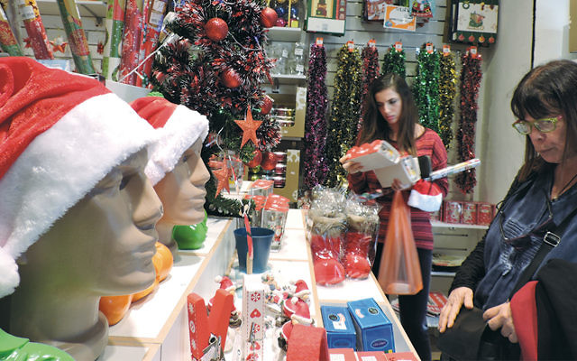 Customers shopping at Joy, a small Tel Aviv store that has been heckled repeatedly for selling Christmas and New Year’s merchandise. (Ben Sales)