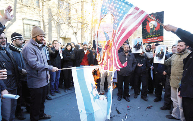 Iranian men burn Israeli and American flags during a demonstration against the execution of prominent Shiite cleric Nimr al-Nimr by Saudi authorities on January 2.
