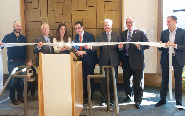 Last Sunday, from left, Mordecai Rosenberg, one of the shul’s past presidents; Mayor Peter Rustin of Tenafly; Rebecca Tobin, the shul’s president; its rabbi, Akiva Block symbolically cutting the ribbon that marks the building as open for business; Mayor Frank Huttle III of Englewood; Lakeland Bank’s vice president for commercial loans, Douglas W. Cosgrove, and another of the shul’s past presidents, Dr. Natie Fox, who is now chair of strategic growth.