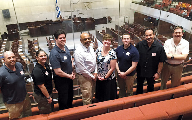 From left, Lafe Bush, Cathy Madalone, John Devine, Dr. James Pruden, Jacqueline Luthcke, Todd Pearl, Timothy Torell, and Kenneth Ehrenberg stand in a gallery at the Knesset.