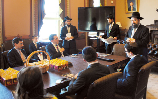 Matt Nosanchuk, seated at the end of table, facing out, at a Purim megillah reading in the White House’s diplomatic reception room on March 24.