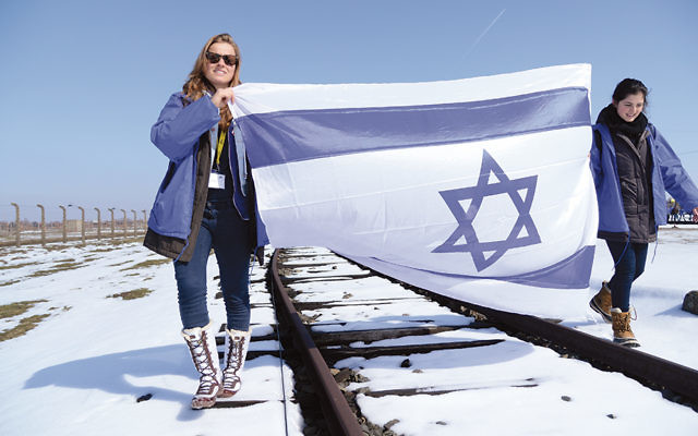 Teenagers walk on the tracks between Auschwitz and Birkenau. (Yossi Veliger)