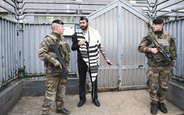 Soldiers guard a staff member at a Chabad school in Paris on November 16, 2015.